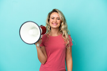 Young Brazilian woman isolated on blue background holding a megaphone and smiling a lot