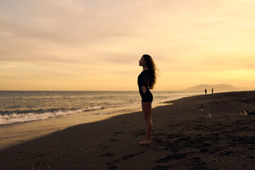 woman doing a yoga practice at the beach while a beautiful sunset