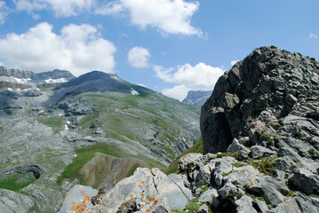 View from the top of a mountainous landscape that blends the green colors of nature and the white snow of the peaks