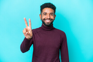 Fototapeta premium Young Brazilian man isolated on blue background smiling and showing victory sign