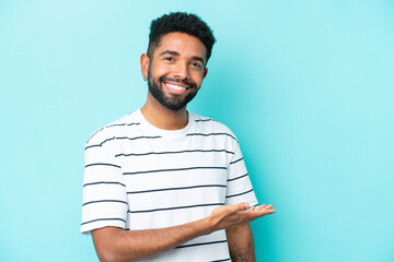 Young Brazilian man isolated on blue background presenting an idea while looking smiling towards