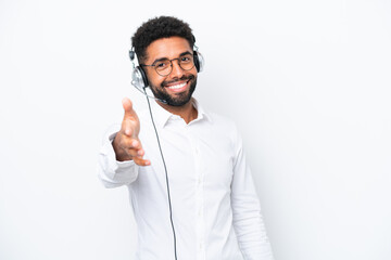 Telemarketer Brazilian man working with a headset isolated on white background shaking hands for...