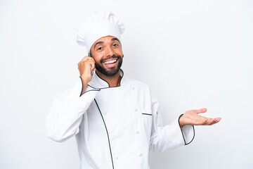 Young Brazilian chef man isolated on white background keeping a conversation with the mobile phone with someone