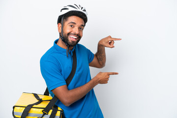 Young Brazilian man with thermal backpack isolated on white background pointing finger to the side and presenting a product