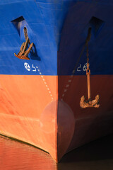 Front view of bow of cargo ship. Close up of vessel bow with anchors and draft mark.