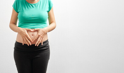 Unrecognizable peaceful pregnant caucasian woman hugging her tummy in front of isolated white...