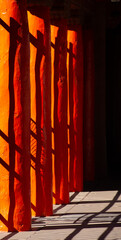 Naklejka premium abstract design of of black shadows on vibrant orange wooden pillars shadows of fence cast on pillars in afternoon sunlight in down town Santa Fe New Mexico near plaza colorful vertical backdrop 