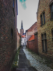Fototapeta na wymiar Historical street with medieval brick houses and a church in Bruges town, Belgium