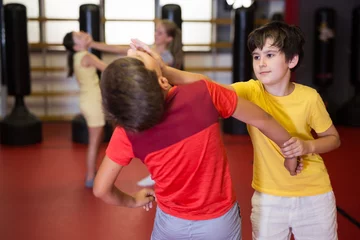 Gordijnen Kids in pairs training chin strike during their self-protection training. © JackF