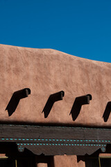 close up of adobe house against blue sky in Santa fe New Mexico with water run off drains abstract...