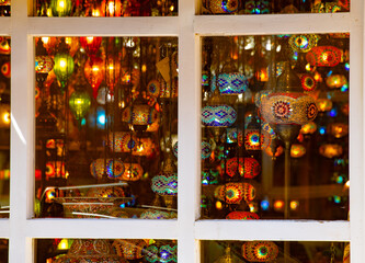 Obraz premium traditional style colored glass lanterns and lights hanging in shop window shot through glass window with white window frame visible detailed painted glass lanterns as souvenirs or interior home 