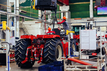 Industrial workers assembles agricultural tractor in workshop