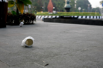 Naklejka na ściany i meble Carelessly thrown away paper cup with plastic on a street in a city