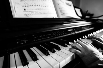 Young child practicing playing a piano with hands resting on keys