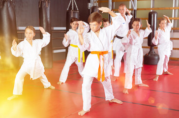 Focused children trying new martial moves in a practice during karate class in gym