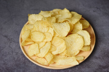 Crispy potato chips on the kitchen table black background, Potato chips snack on plate -  top view