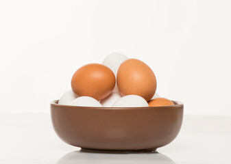 brown bowl with white and brown chicken eggs on white background
