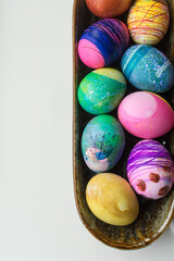 Easter eggs decorated and dyed by young children in a ceramic bowl on a white background