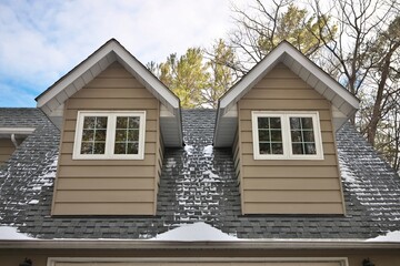 Low Angle View of Dormers Above a Garage in a Home with Beige Gray Wood Siding