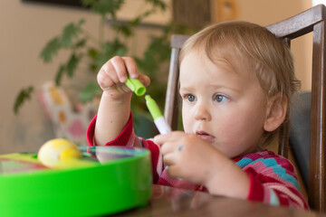 Toddler puts the cap back on a marker while doing an Easter egg craft; DIY arts and crafts with kids - obrazy, fototapety, plakaty