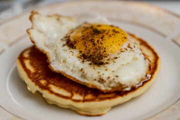 American breakfast. Fried egg over a pancake.
