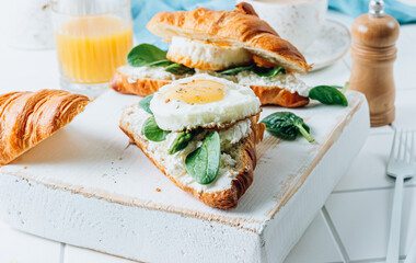 Delicious Breakfast with Croissant sandwiches with Fried Egg, spinach, and Coffee and Orange Juice on white background,