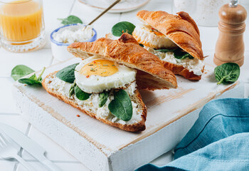 Delicious Breakfast with Croissant sandwiches with Fried Egg, spinach, and Coffee and Orange Juice on white background,