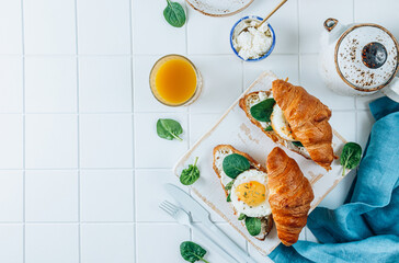 Delicious Breakfast with Croissant sandwiches with Fried Egg, spinach, and Coffee and Orange Juice on white background,
