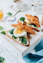 Delicious Breakfast with Croissant sandwiches with Fried Egg, spinach, and Coffee and Orange Juice on white background,