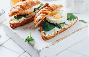 Delicious Breakfast with Croissant sandwiches with Fried Egg, spinach, and Coffee and Orange Juice on white background,