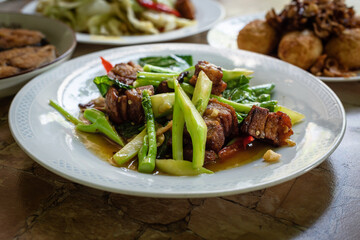 Stir fried kale vegetables with fried pork in the plate for breakfast or lunch or dinner,some menu on food table