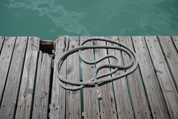 Naklejka premium Old wooden boat dock with rope by ocean water
