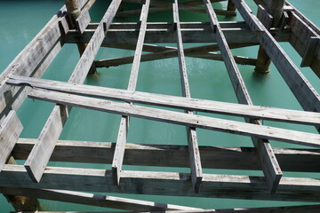 Partial wooden boat dock boards with turquoise ocean water below