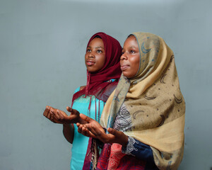 Two African Nigerian female muslim sisters or friends with Hijab scarf, engaging the process of...