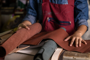 Tanner woman selective leather goods on workshop, Selected pieces of beautifully colored or tanned...