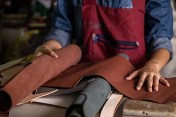 Deurstickers Tanner woman selective leather goods on workshop, Selected pieces of beautifully colored or tanned leather on leather craftman work desk, Working process of leather craftsman. © Kalyakan