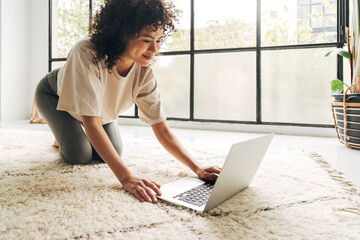 Multiracial latina woman in sports clothes searching fitness video tutorial with laptop to exercise...