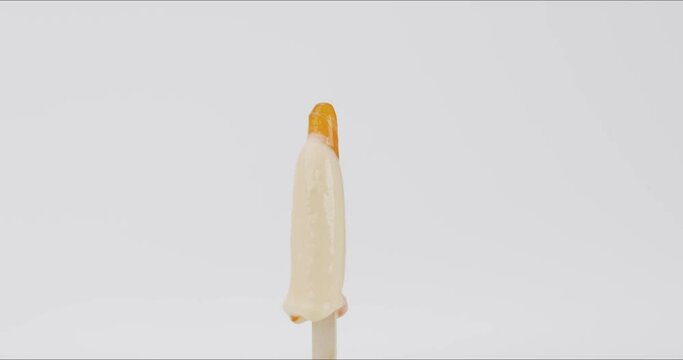 Time-lapse melting ice cream on a stick on white background.