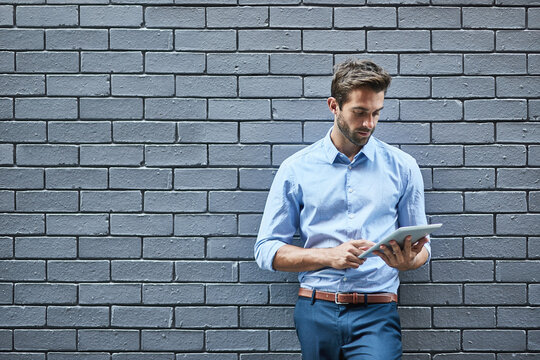 Hes got the look. Shot of a handsome young businessman standing against a grey facebrick wall.