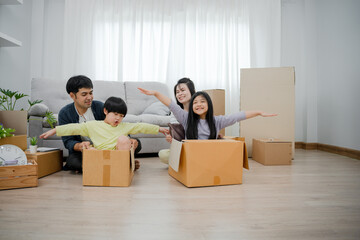 Fototapeta na wymiar Smiling and laughing Asian family is happy in new home. Cute son and daughter help move things. Parents and children help to arrange things. family day activities together on moving day