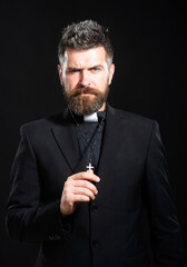 Religion concept. Handsome hispanic catholic priest man over black isolated background. Pastor or...
