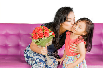 Mother kiss daughter while receiving flowers