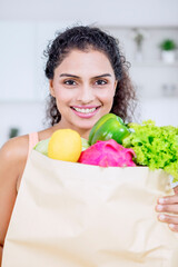 Smiling woman holding vegetables in the kitchen