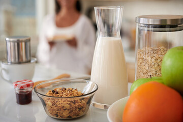 Bowl of granola, bottle of milk and fresh fruits on kitchen table