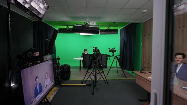 Backstage, news anchors at work, journalist interview a businesswoman, view of a backstage studio TV news shooting, chroma key template.