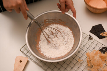 Top view, Female using a whisk to stir cookie flour with a chocolate cookie dough