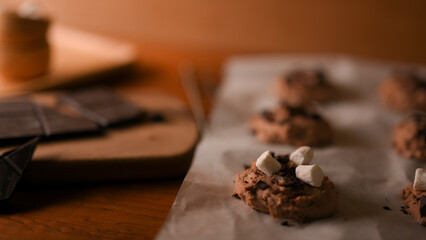 Chocolate chip cookies dough with tiny marshmallow on a baking sheet.