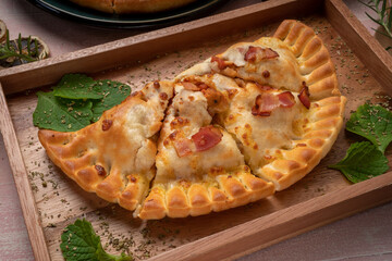 Pizza puff ham cheese on white wooden plate on wooden background. 