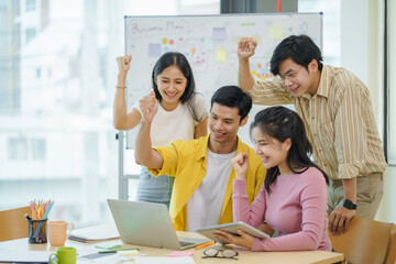 Successful group of young Asian business people achieving goals excited raised hands rejoicing. New startup project concept.