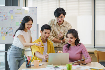 Group of young Asian business people brainstorming, looking at laptop computer.